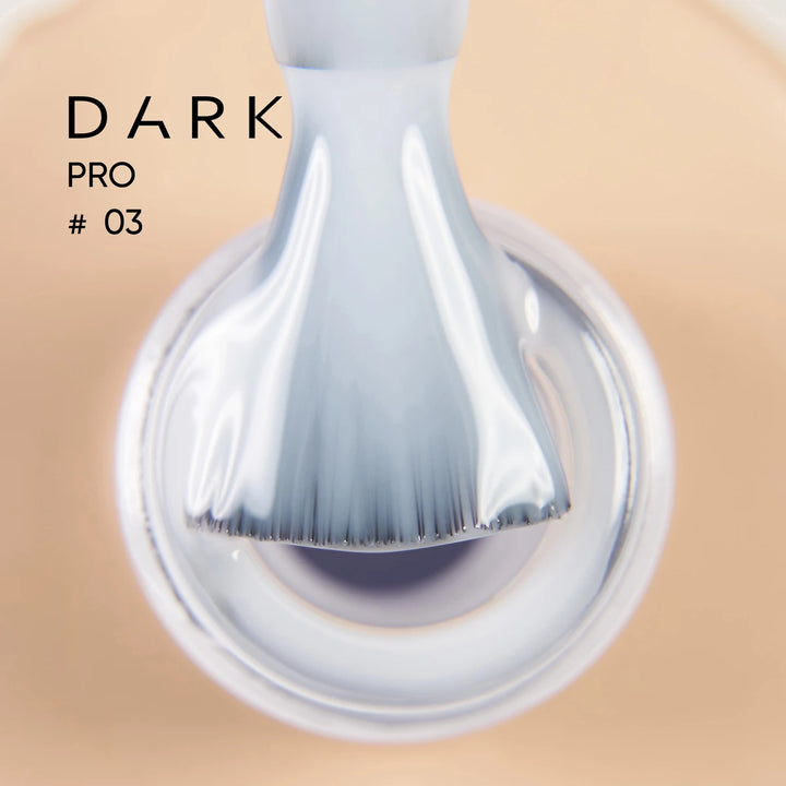 Close-up of nail polish brush with milky nude gel, labeled Dark Pro 
