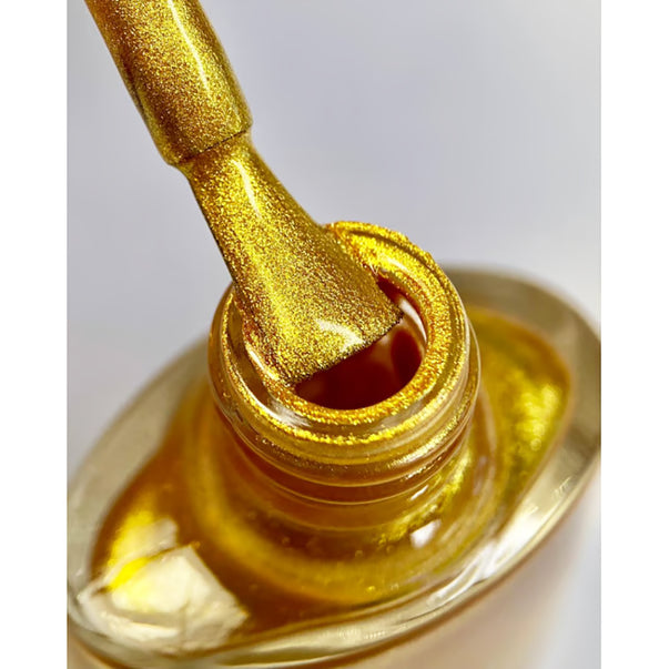 Close-up of gold shimmer nail polish brush and bottle for manicure