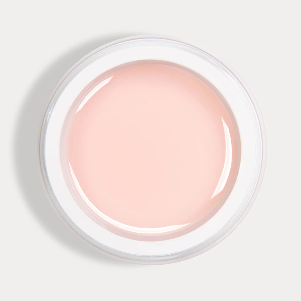 Open jar of pale pink UV gel nail polish for manicure on white background