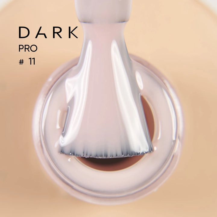 Close-up of brush applying nude gel nail polish, labeled DARK PRO 