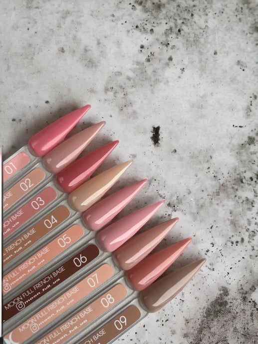 Assorted French base nail gel color swatches in nude and pink shades on marble surface