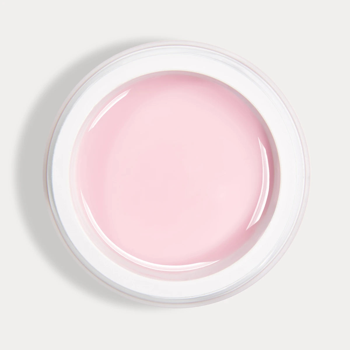 Open jar of light pink UV gel for nails, viewed from above on a plain background.