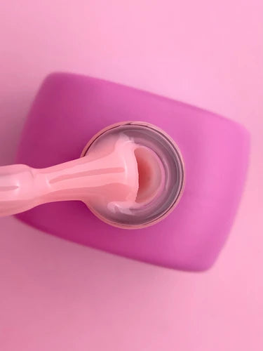 Pink builder gel for nails in a jar with spatula on pink background, manicure supplies