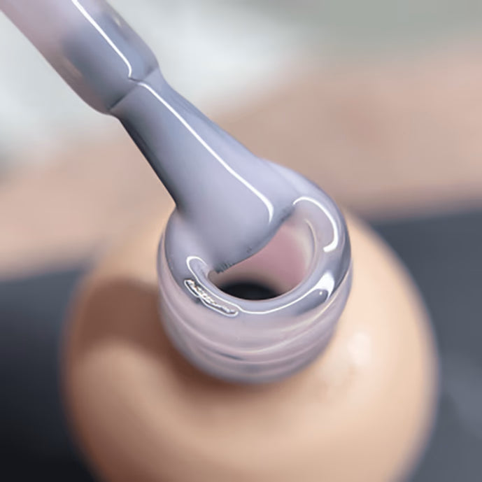 Close-up of nail polish brush dipped in pastel UV gel polish bottle