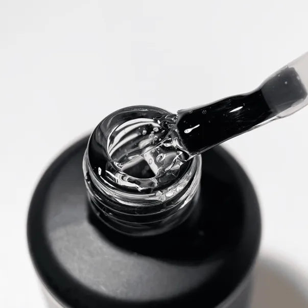 Clear UV gel polish in an open bottle with brush for professional manicure