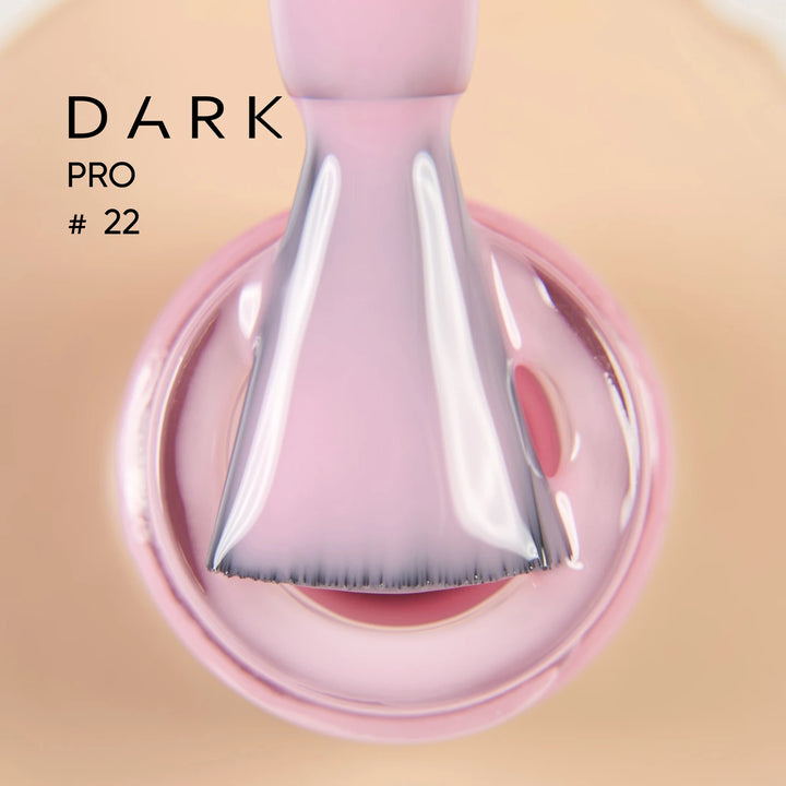 Close-up of a nail polish brush dipped in light pink UV gel polish, labeled Dark Pro 