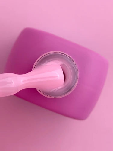 Pink nail gel polish bottle with brush, close-up, on a pink background