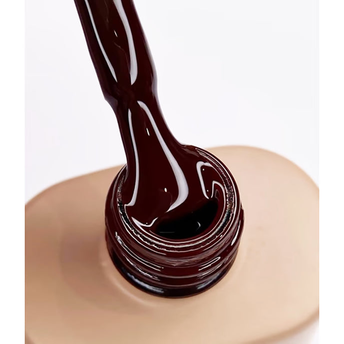 Close-up of dark brown UV gel nail polish bottle with brush applicator