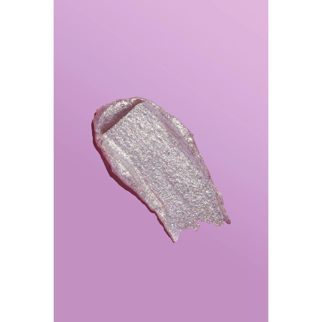 A textured swipe of shimmering metallic pink lip gloss or cream makeup on a solid pink background.