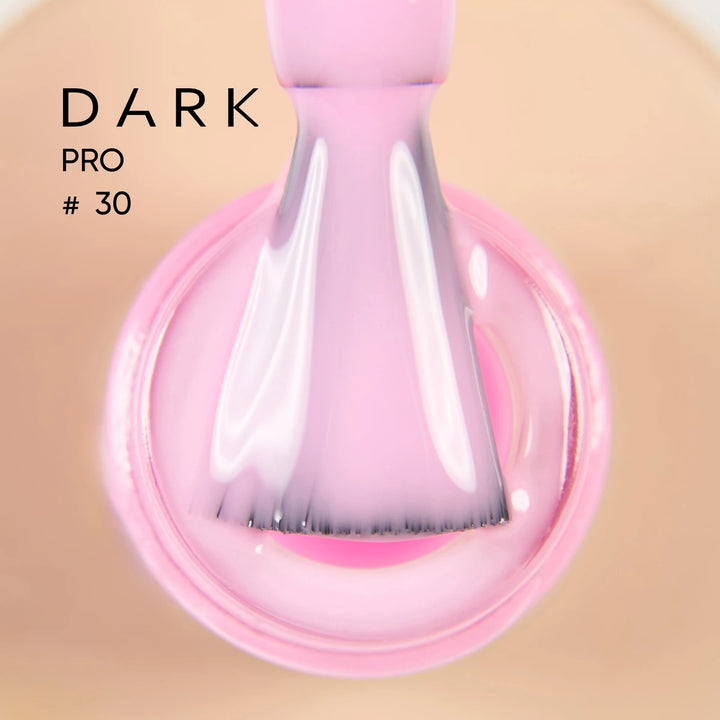 Close-up of a nail polish brush with glossy light pink UV gel for manicures.