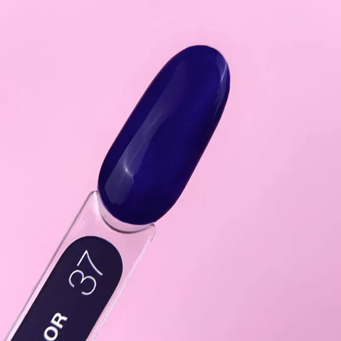 Nail polish color swatch in deep navy blue on a sample stick against a pink background