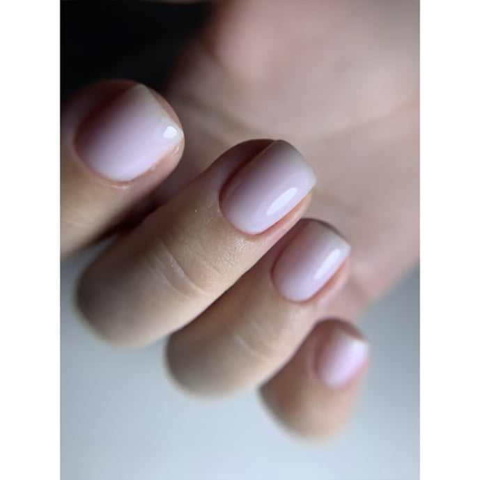 Hand with short nails featuring glossy pale pink UV gel manicure