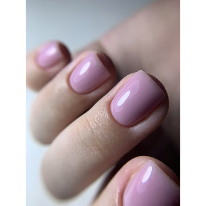 Close-up of hand with glossy light pink gel manicure nails