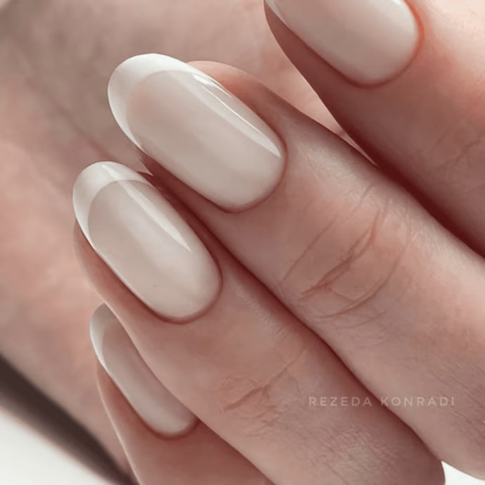 Close-up of manicured hand with glossy nude gel polish, perfect for natural nail look