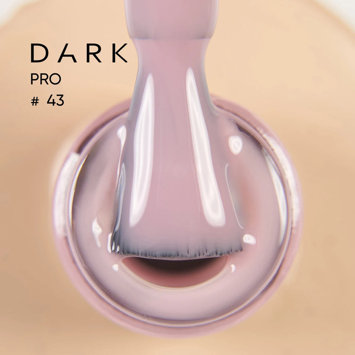 Close-up of soft mauve gel nail polish on brush, labeled Dark Pro 43, for manicures.