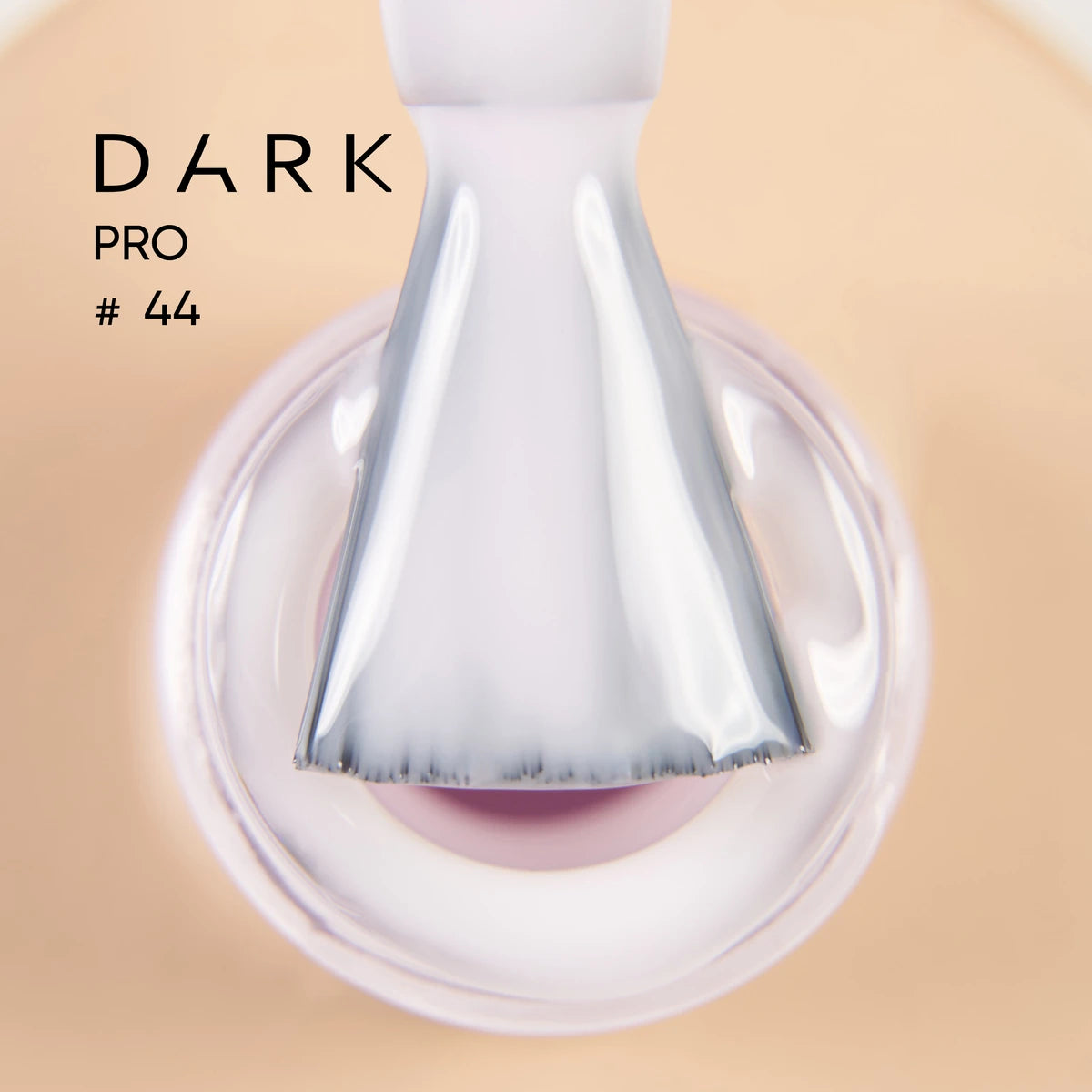 Close-up of brush applying sheer light pink UV gel nail polish, labeled Dark Pro #44.