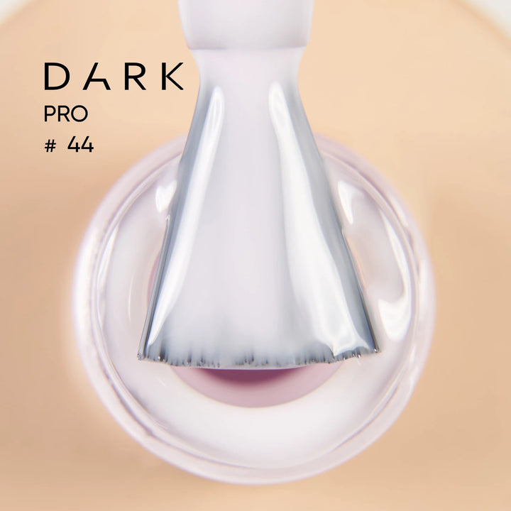 Close-up of brush applying sheer light pink UV gel nail polish, labeled Dark Pro 