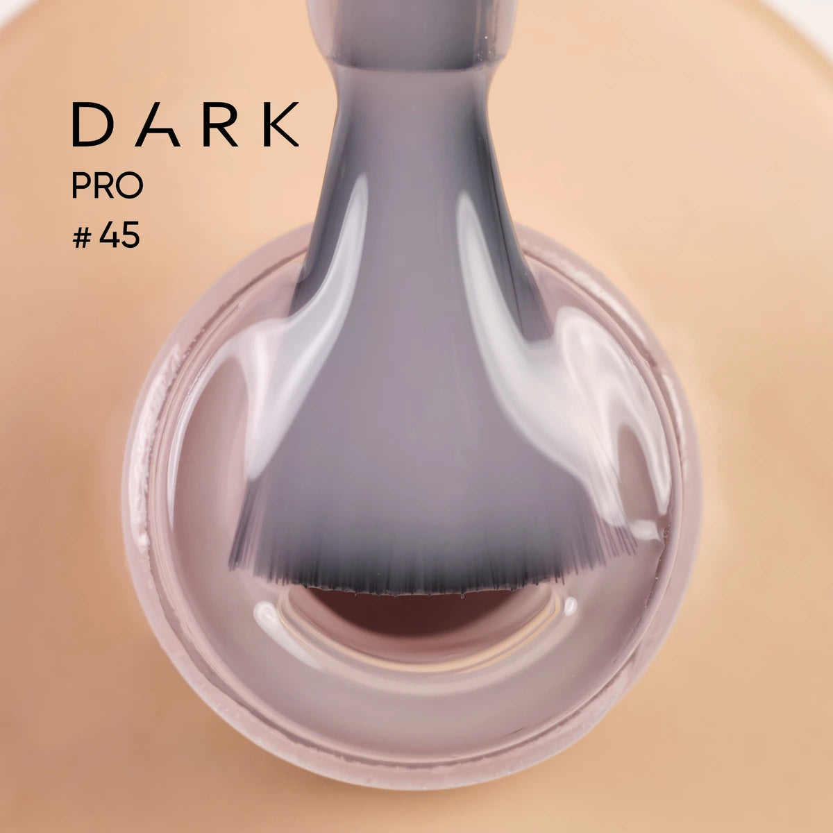 Close-up of a nail polish brush dipped in nude gel polish, labeled DARK PRO #45.