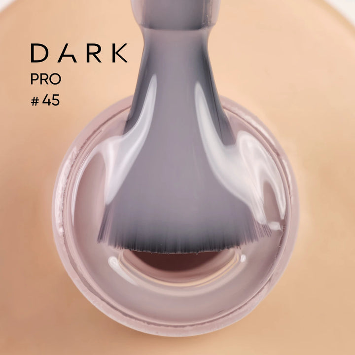 Close-up of a nail polish brush dipped in nude gel polish, labeled DARK PRO 