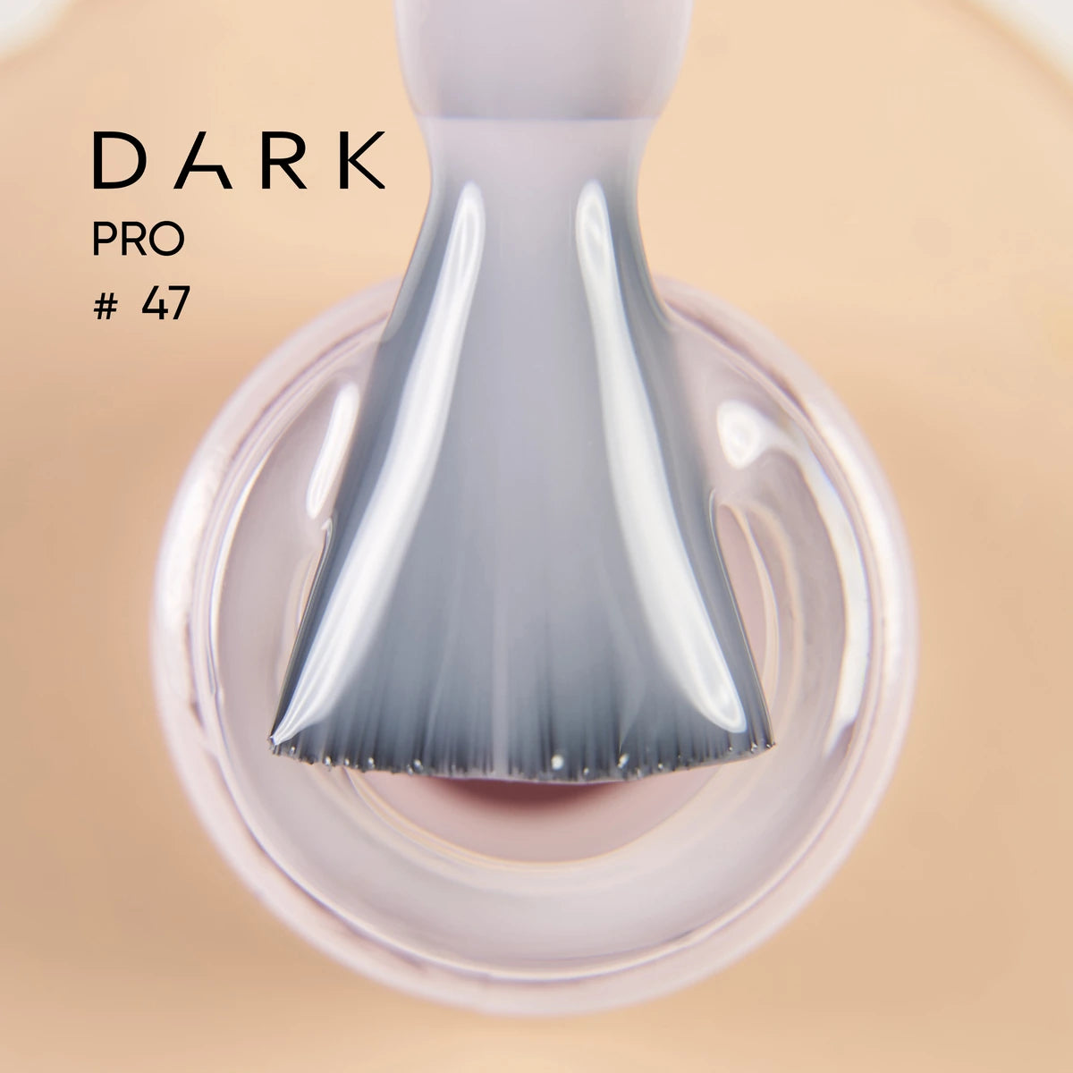 Close-up of nail polish brush with glossy light pink gel, Dark Pro #47 text visible