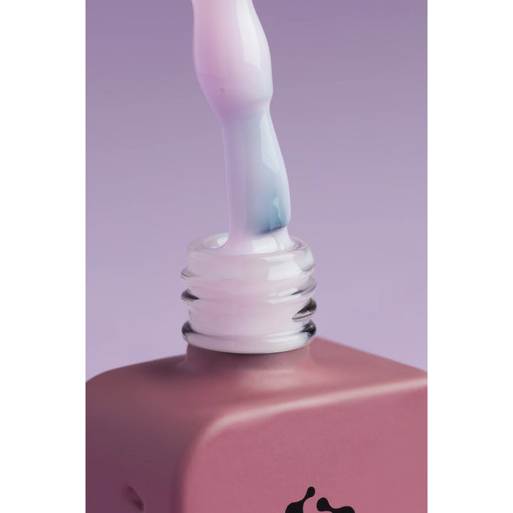 Close-up of pastel pink gel nail polish bottle and brush on purple background