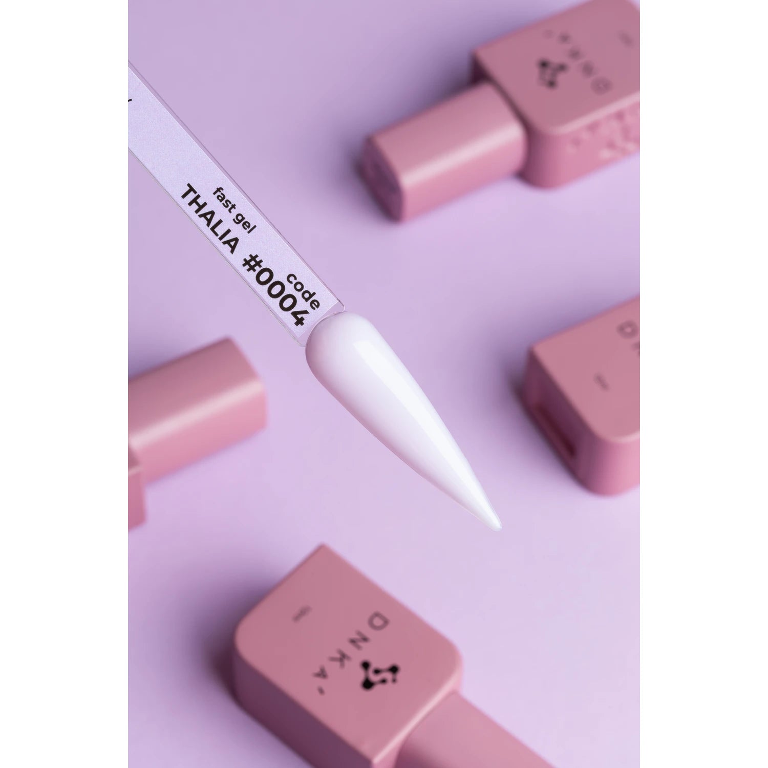 White UV gel polish sample on nail display stick with pink polish bottles on purple background