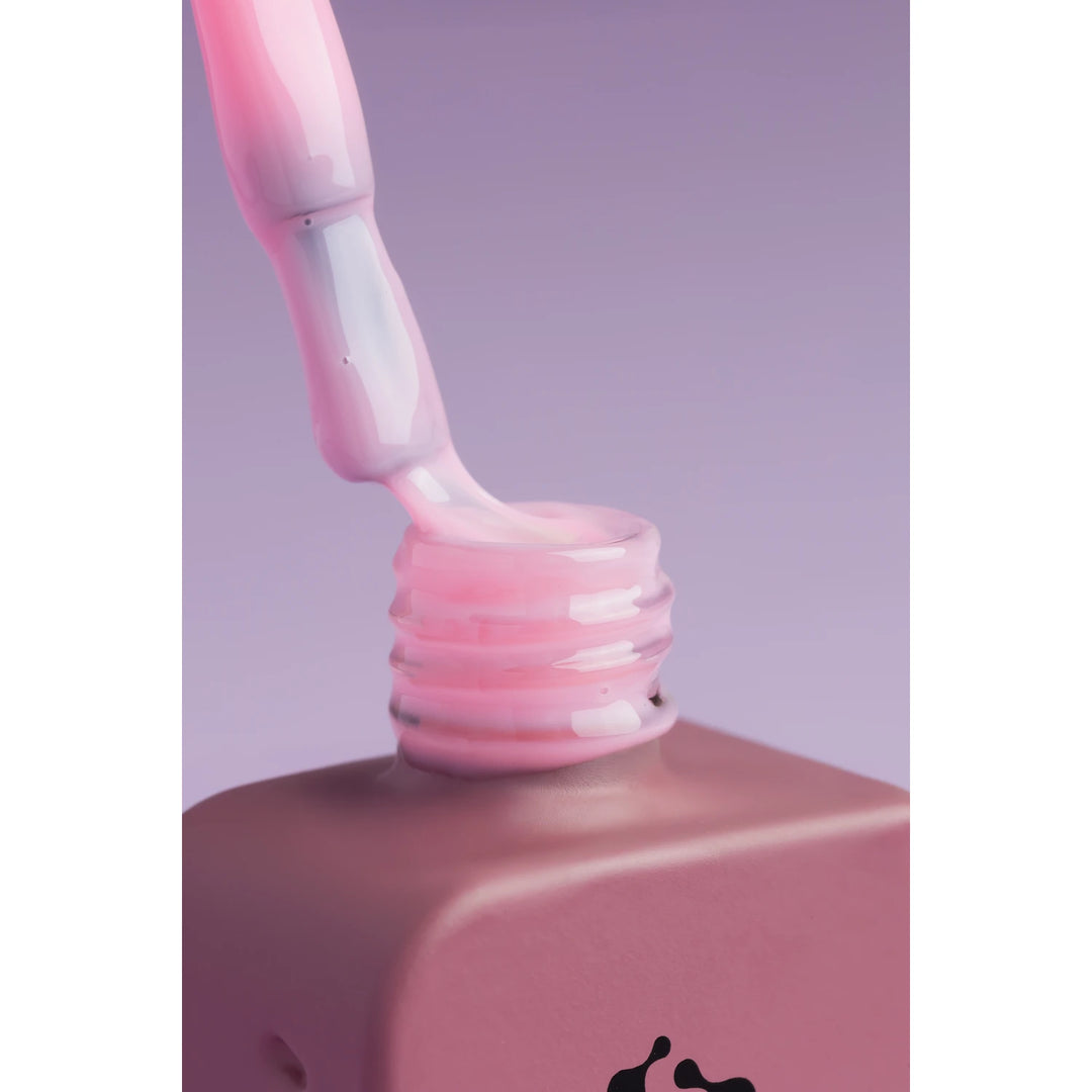Close-up of pink UV gel nail polish bottle with brush on purple background