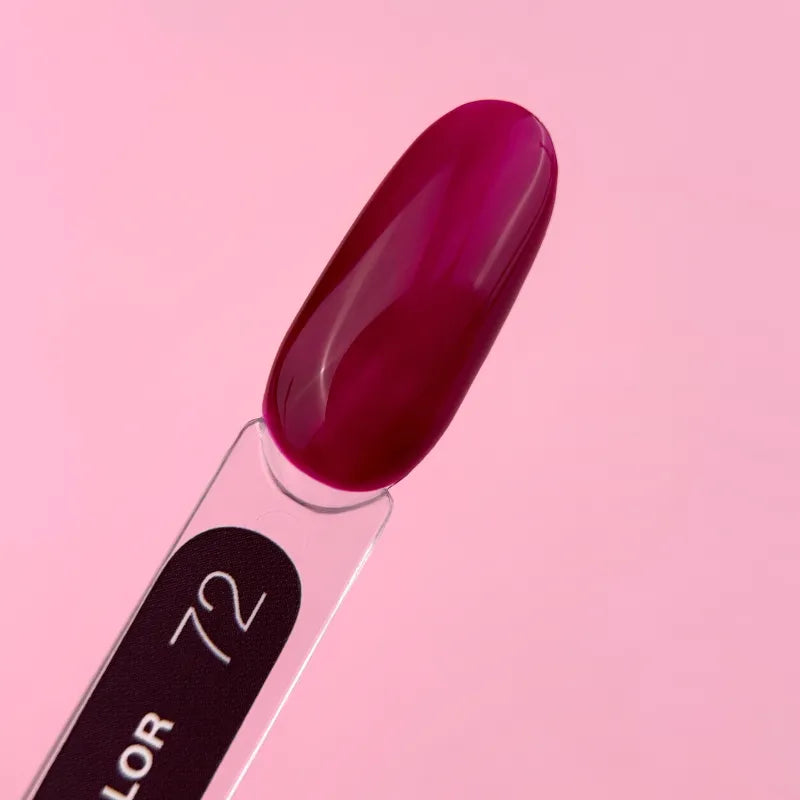 Swatch of deep magenta UV gel nail polish on transparent stick, pink background