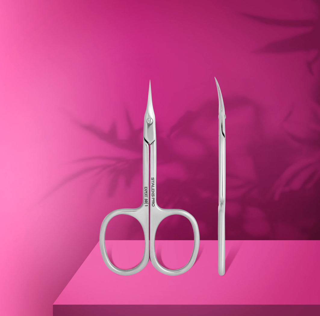 Professional stainless steel manicure scissors with curved tip on pink background