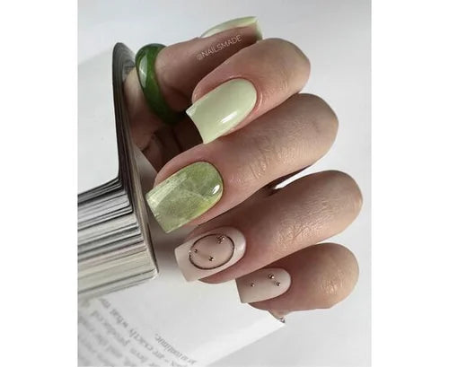 Hand with green and nude gel nail art, marble accent and gold studs, manicure close-up