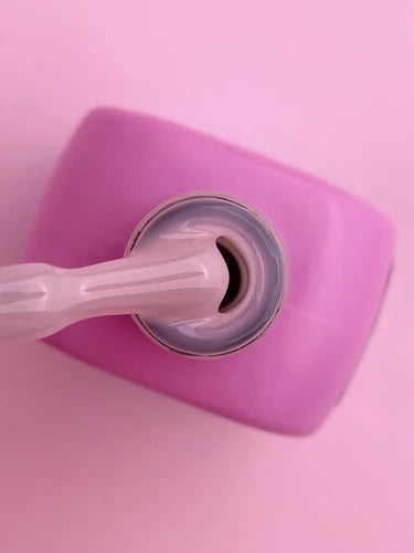 Open nail polish bottle with brush, pink background, professional manicure product