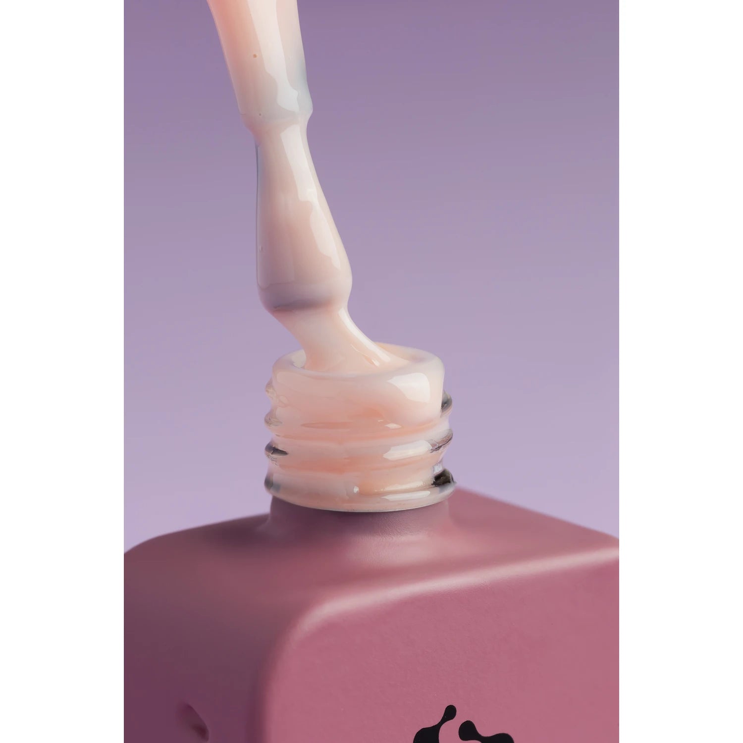Close-up of pink nude UV gel polish bottle with brush on purple background, manicure product