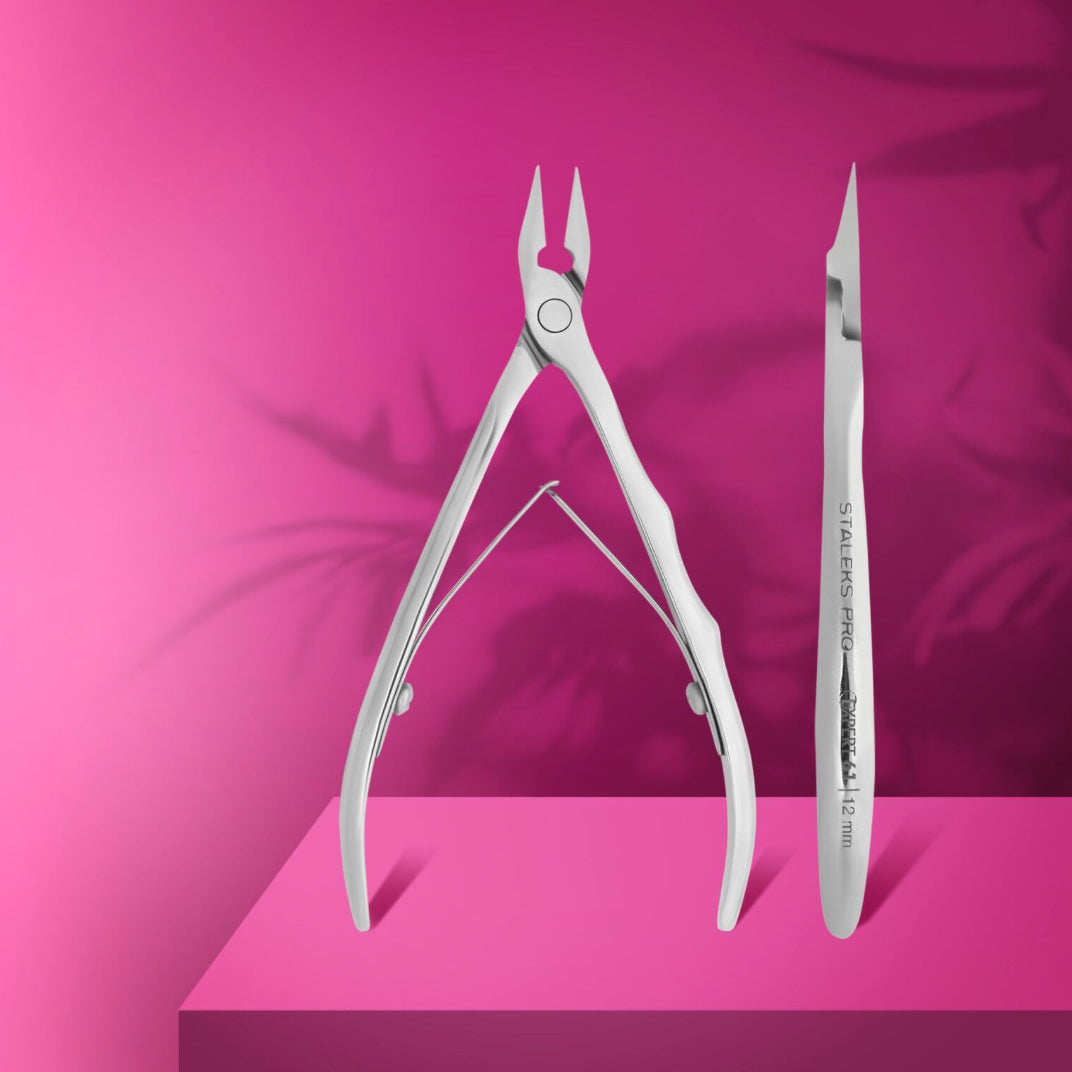 Professional stainless steel nail cuticle nippers and tool on pink background for manicure