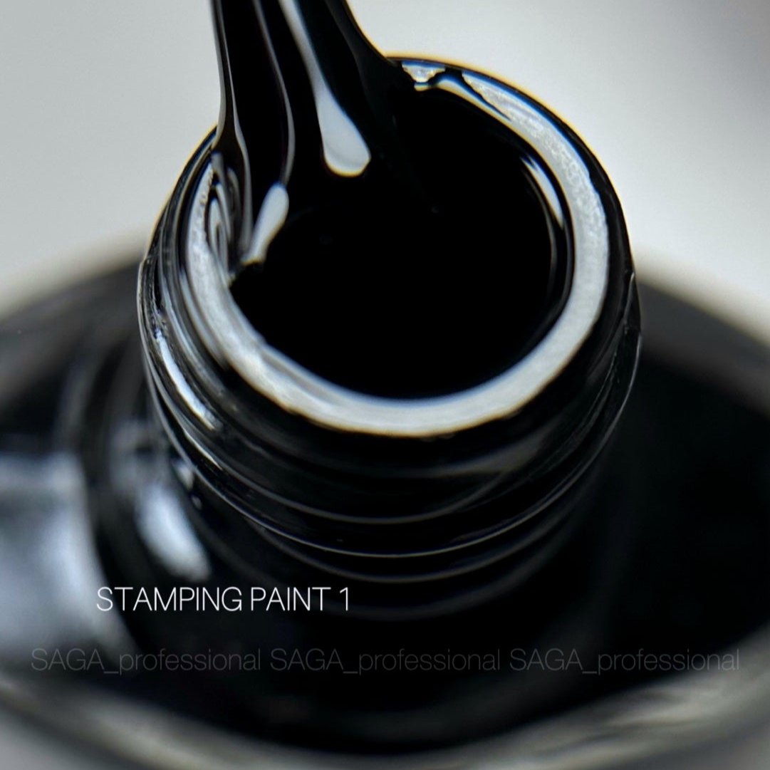Close-up of a brush lifting black stamping nail paint from an open bottle