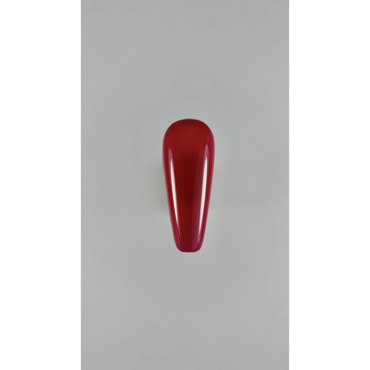 Glossy red nail polish swatch on artificial nail tip, manicure product display