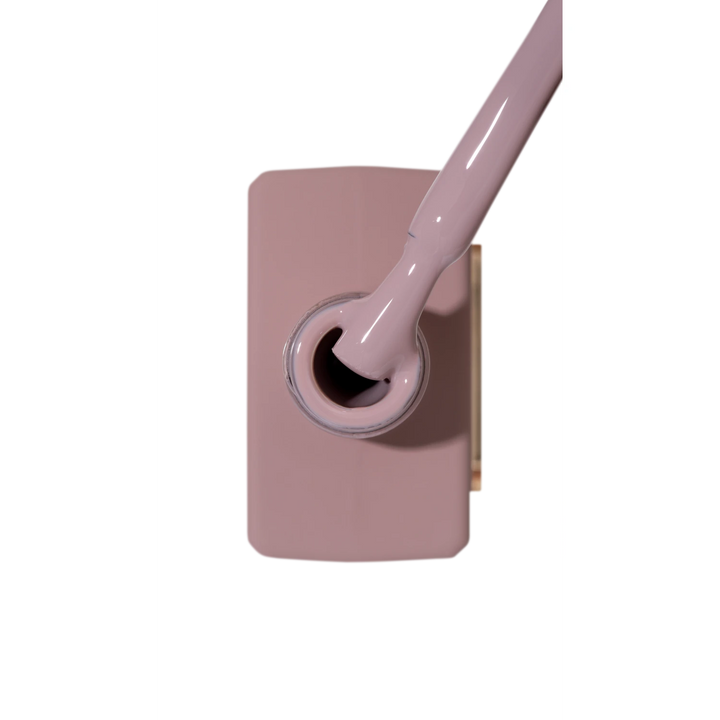 Open bottle of mauve nail gel polish with brush applicator