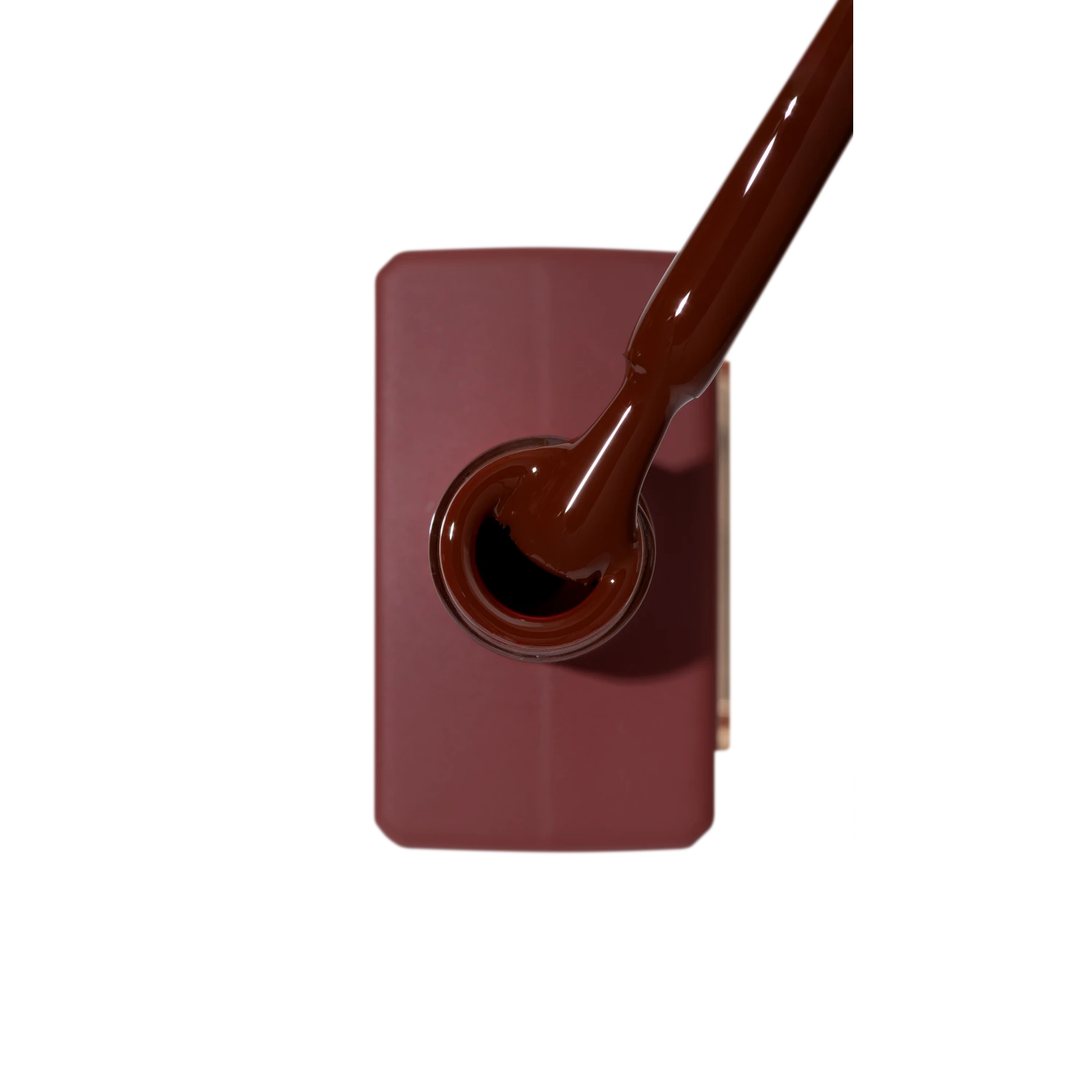Brown gel nail polish bottle with applicator brush, top view, professional manicure supply