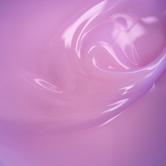 Close-up of glossy pink builder gel for nails with smooth, creamy texture