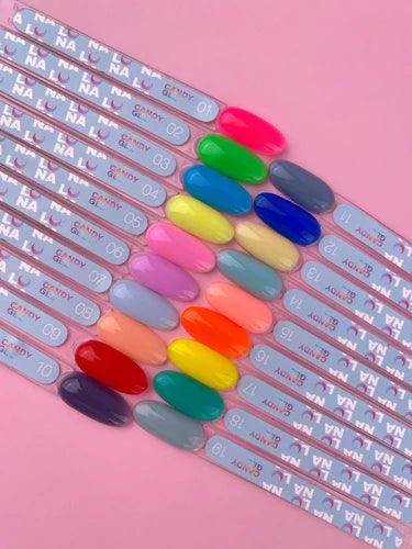 Assorted colorful UV gel nail polish swatches arranged on clear sample sticks on a pink background