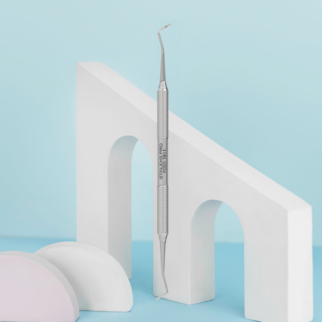 Stainless steel professional cuticle pusher for manicure on a minimalist pastel background