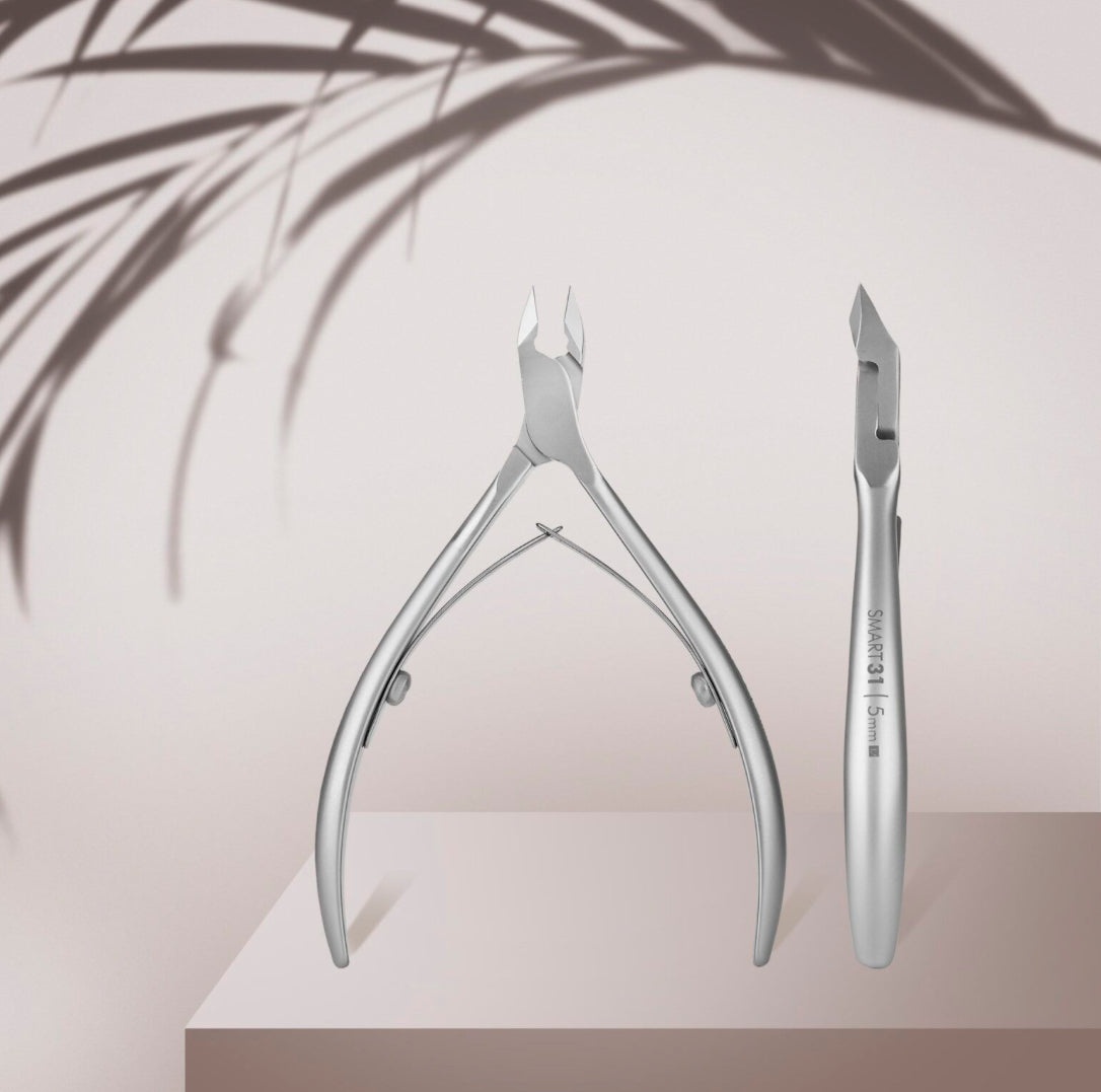 Stainless steel cuticle nippers for manicure and pedicure on a soft pink background