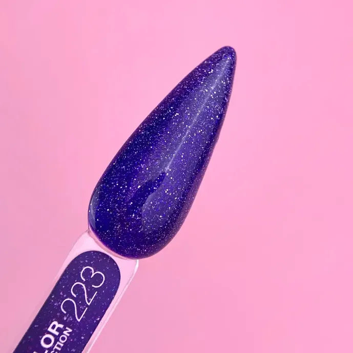 Purple glitter gel nail polish swatch on display stick labeled 223, pink background