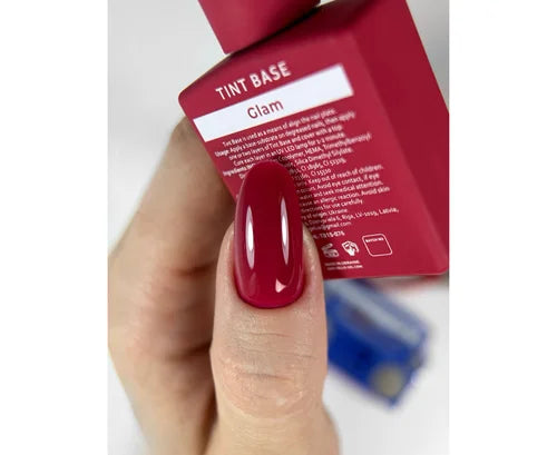 Hand with red nail polish holding a red product packaging labeled &