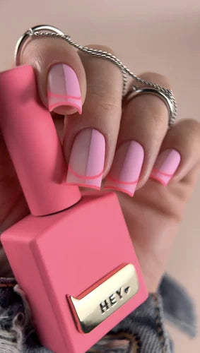 Hand with pink French tip gel nails holding pink nail polish bottle, manicure product