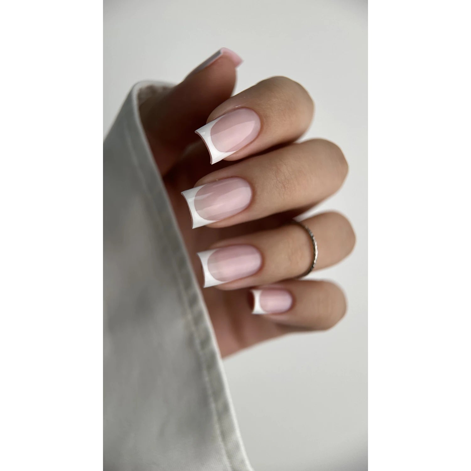 Close-up of hand with classic French manicure, square-shaped nails, pink and white polish
