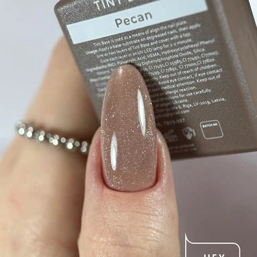 Hand with glossy pecan brown gel nail polish, holding matching nail product bottle.