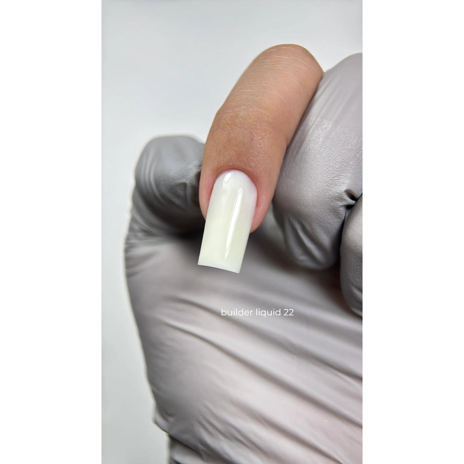 Hand in glove holding finger with glossy milky white builder gel nail, manicure close-up