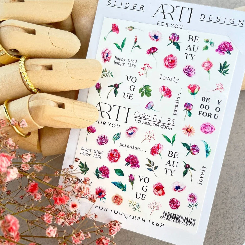 Colorful floral nail art stickers with text designs on a sheet, held by a wooden hand model.