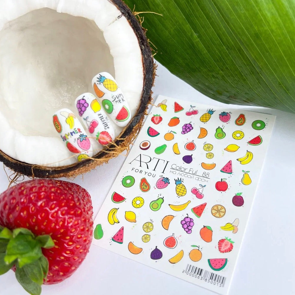 Colorful fruit nail stickers on artificial nails, displayed in a coconut with strawberry, tropical nail art accessories