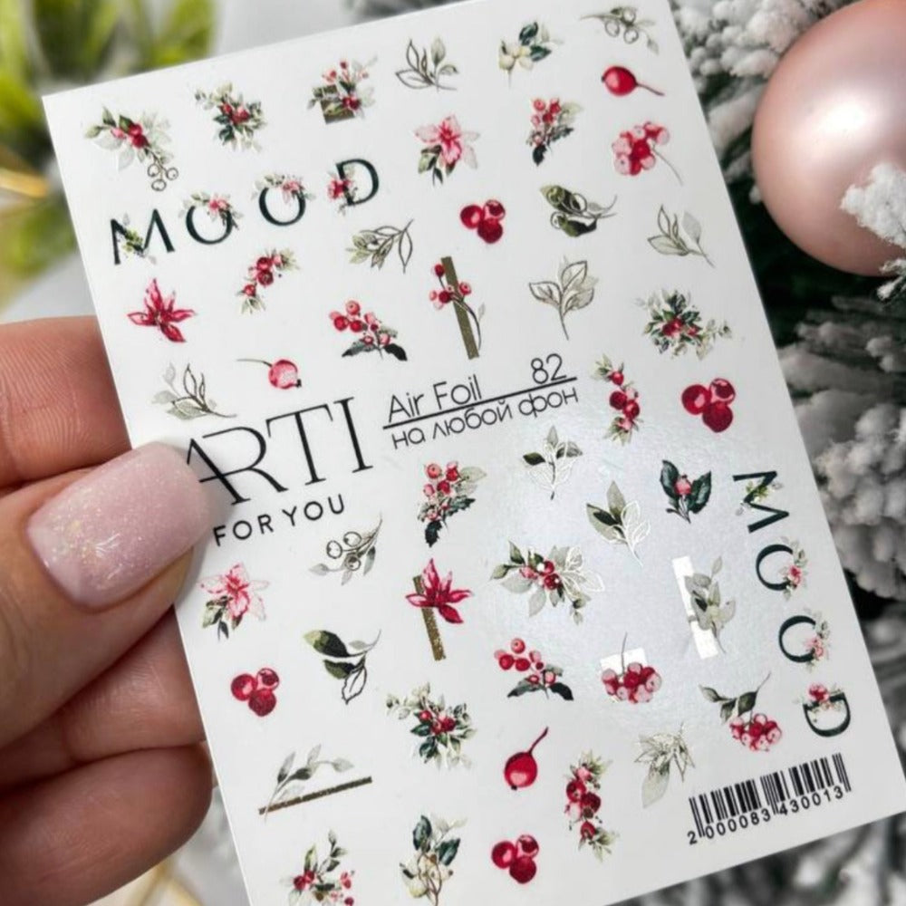 Floral and berry nail art stickers sheet held by a hand with pastel manicured nails